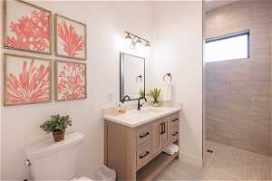 Bathroom with large vanity, a tile shower, and toilet