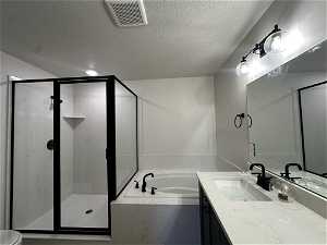 Full bathroom featuring vanity, toilet, separate shower and tub, and a textured ceiling