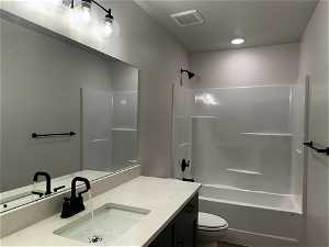 Full bathroom with vanity, toilet, shower / tub combination, and a textured ceiling