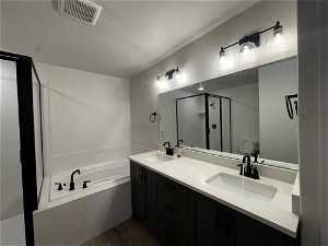 Bathroom with hardwood / wood-style floors, a textured ceiling, dual bowl vanity, and a bath