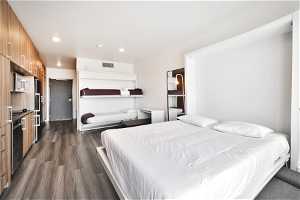 Bedroom with dark hardwood / wood-style flooring and stainless steel refrigerator