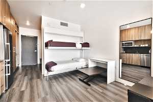 Bedroom with dark hardwood / wood-style floors, a closet, and stainless steel fridge