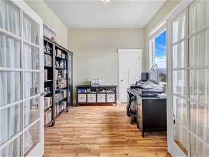 Office with light hardwood / wood-style floors and french doors