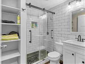 Bathroom featuring walk in shower, vanity, tasteful backsplash, toilet, and tile walls