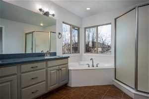 Bathroom with double sinks, walk-in shower, separated jetted tub and tile flooring