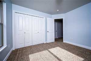 Unfurnished bedroom featuring a textured ceiling, carpet, and a closet