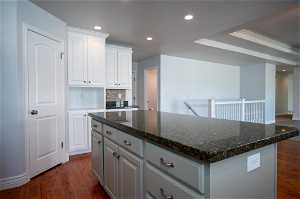 Kitchen with white cabinetry, dark hardwood flooring, a center island