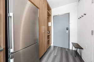 Kitchen featuring open shelves, freestanding refrigerator, dark wood-style floors, modern cabinets, and brown cabinetry