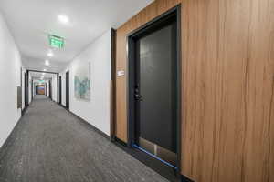 Corridor with dark colored carpet and recessed lighting