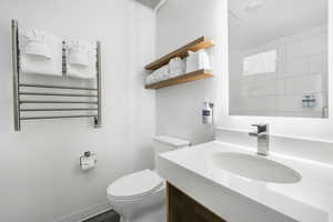 Full bath featuring radiator heating unit, a towel warmer, vanity, and dark wood-style flooring