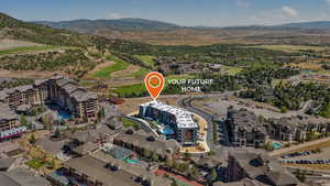 Aerial view of property's location featuring a mountainous background and apartment complex