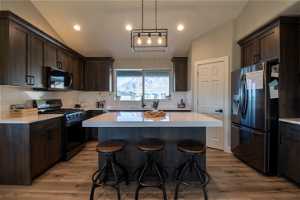 Kitchen with light hardwood / wood-style floors, black range with gas stovetop, a center island, and stainless steel fridge with ice dispenser