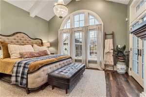 Bedroom with dark hardwood/wood flooring, french doors, a chandelier, high vaulted ceiling, and beam ceiling