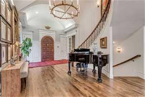 Foyer featuring wood flooring, a notable chandelier, and high vaulted ceiling