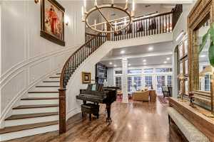 Foyer entrance featuring decorative columns, dark wood flooring, a notable chandelier, and a towering ceiling