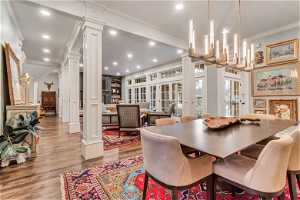 Dining space with light hardwood / wood flooring, crown molding, and ornate columns