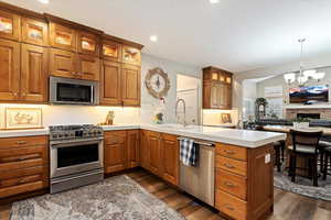 Kitchen with inviting chandelier, a stone fireplace, appliances with stainless steel finishes, and decorative light fixtures