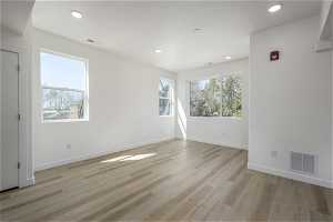 Unfurnished room featuring a healthy amount of sunlight and light hardwood / wood-style flooring
