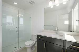 Bathroom featuring vanity, tile flooring, a shower with shower door, and toilet