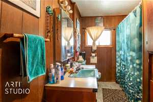 Bathroom featuring  vanity, toilet, wooden walls, and tile floors