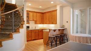 Kitchen with light hardwood / wood-style floors, kitchen peninsula, sink, and a breakfast bar