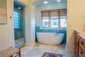 Bathroom with vanity, tile walls, tile floors, and plus walk in shower