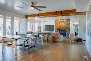 Game room with a fireplace, light hardwood / wood-style flooring, ceiling fan, and beam ceiling