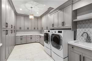 Laundry area with sink, washing machine and clothes dryer, light tile floors, and cabinets