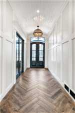 Entrance foyer with dark parquet flooring, wooden ceiling, and french doors