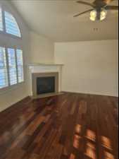 Unfurnished living room featuring dark hardwood / wood-style floors, ceiling fan, a textured ceiling, and lofted ceiling