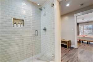 Bathroom featuring hardwood / wood-style floors, ceiling fan, and walk in shower