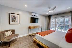 Bedroom featuring light hardwood / wood-style floors, a wall unit AC, ceiling fan, and access to outside
