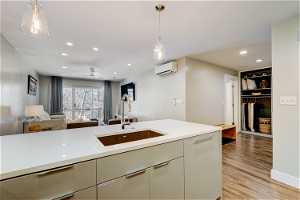 Kitchen with ceiling fan, light hardwood / wood-style flooring, hanging light fixtures, sink, and a wall unit AC