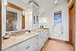 Bathroom featuring backsplash, vaulted ceiling, tile flooring, and oversized vanity
