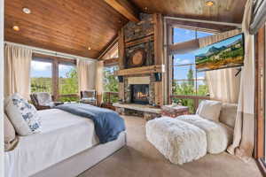 Bedroom featuring beamed ceiling, a stone fireplace, high vaulted ceiling, carpet flooring, and wood ceiling