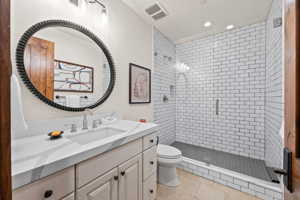 Bathroom with a shower with door, tile flooring, toilet, and vanity