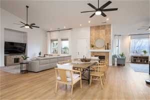 Dining room with light hardwood / wood-style floors, ceiling fan, and a tile fireplace