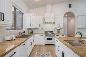 Kitchen featuring white cabinetry, tasteful backsplash, white appliances, sink, and vaulted ceiling