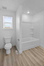 Bathroom featuring bathtub / shower combination, toilet, and hardwood / wood-style flooring