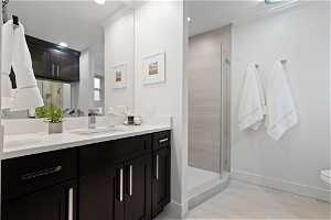 Bathroom with an enclosed shower, ornamental molding, toilet, tile flooring, and dual vanity