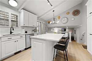 Kitchen with white cabinetry, a kitchen island, a chandelier, sink, and dishwasher