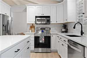 Kitchen with sink, light hardwood / wood-style floors, stainless steel appliances, and white cabinets