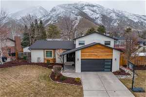 View of front of home with a mountain view, a front yard, and a garage