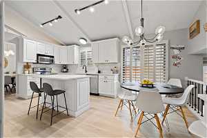 Kitchen with pendant lighting, stainless steel appliances, a chandelier, a kitchen island, and rail lighting