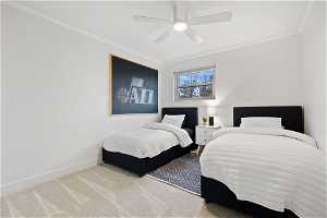 Carpeted bedroom featuring ceiling fan and ornamental molding