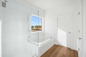 Full bath with a shower stall, a garden tub, and wood finished floors