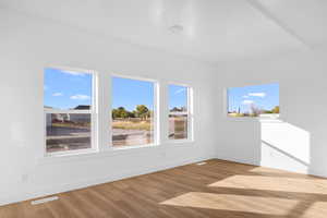 Unfurnished room with light wood-style flooring and beamed ceiling