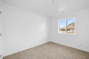 Unfurnished room with light colored carpet and a mountain view