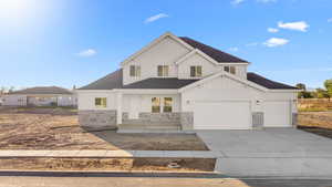 Modern farmhouse with covered porch, board and batten siding, stone siding, a shingled roof, and concrete driveway