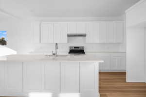 Kitchen with white cabinets, stainless steel electric range, and light wood-style floors